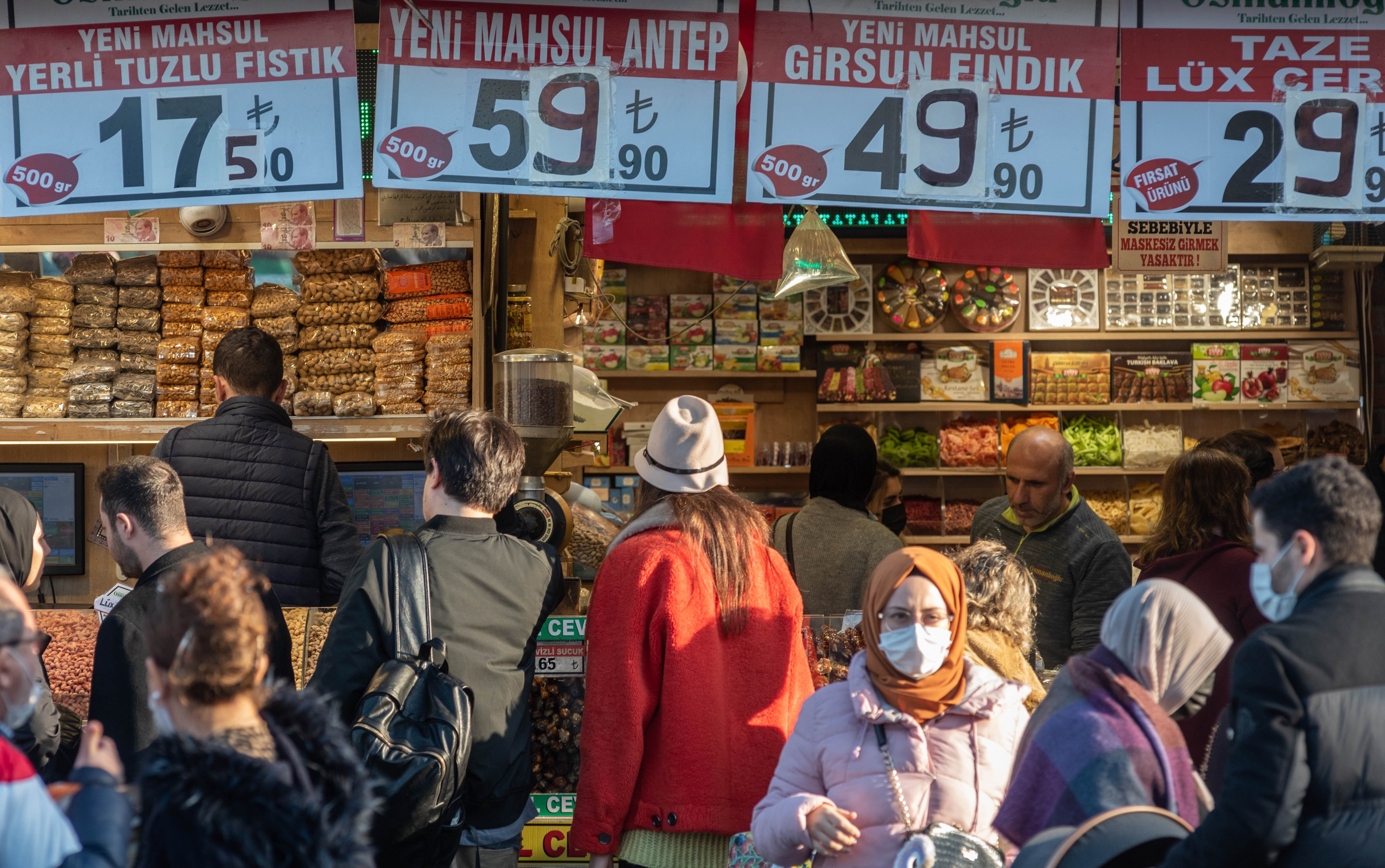Customers at a food market in Istanbul, signs with raised prices
