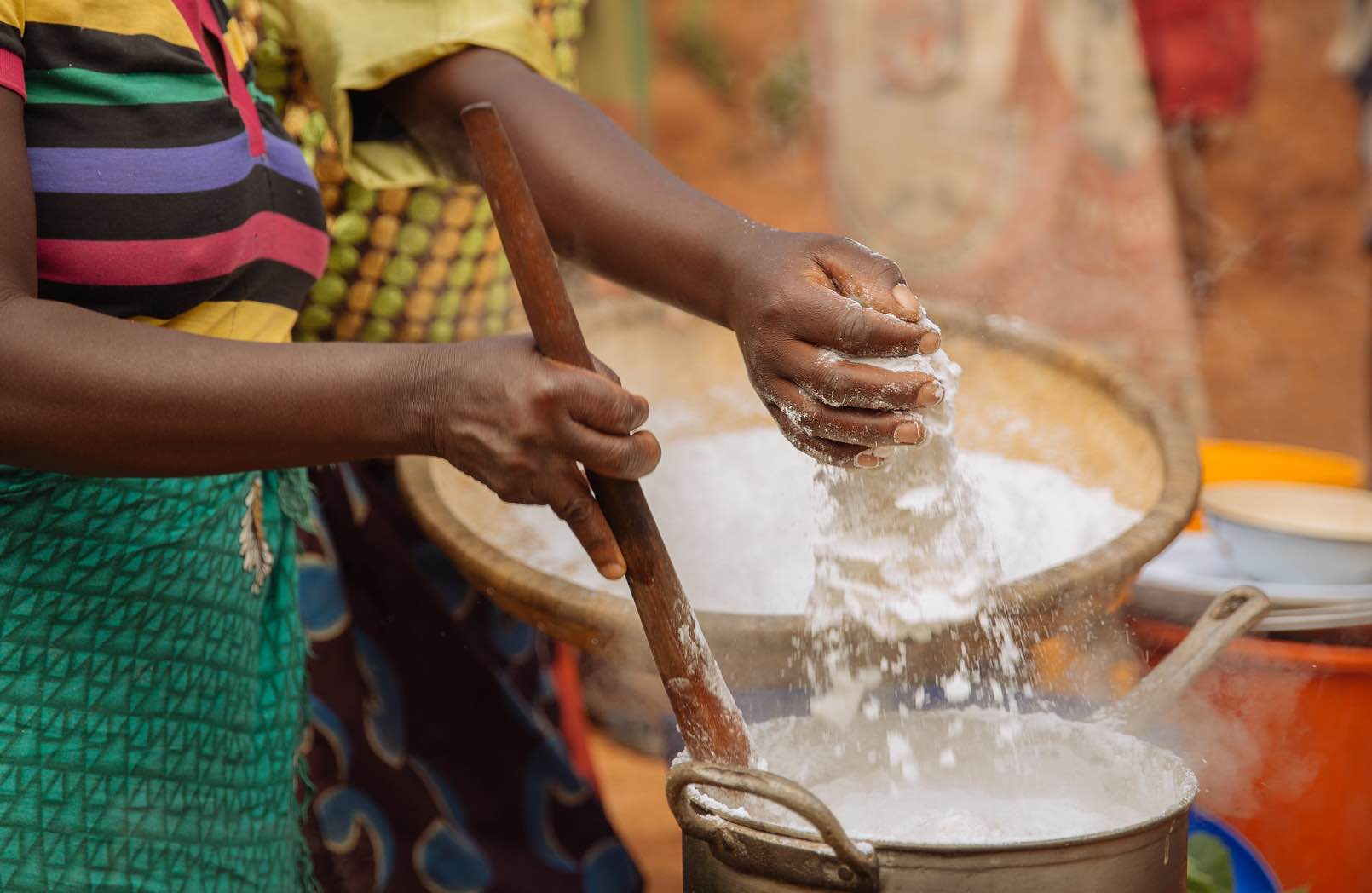 Adding maize flour to a cooking pot in Malawi