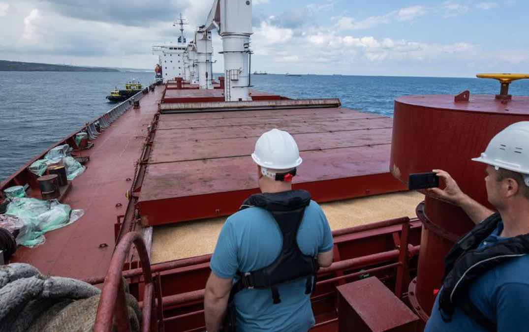 Two men on a cargo ship overlooking grain in hold