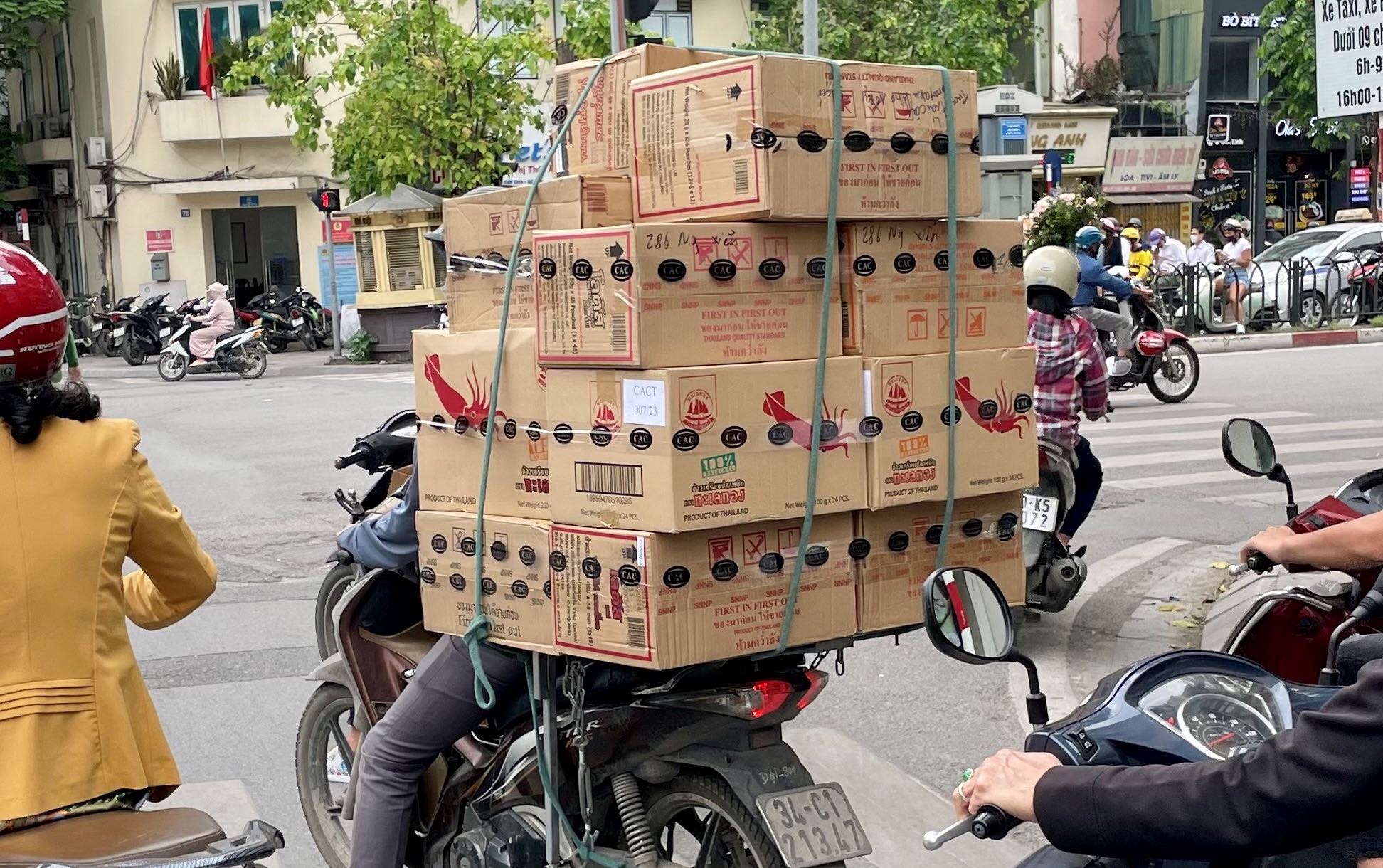 A motorcycle in traffic stacked high with boxes of shrimp